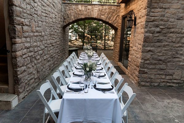 A long table set for dinner beneath a brick archway