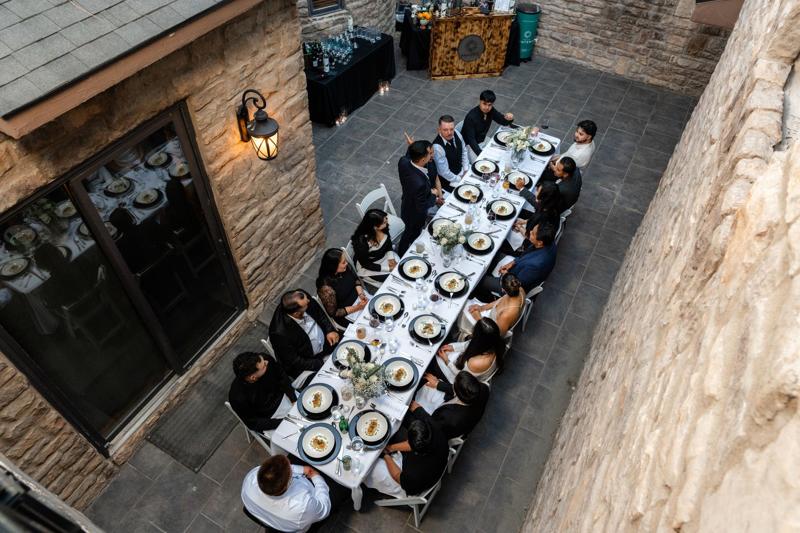 Guests at a long courtyard dinner table